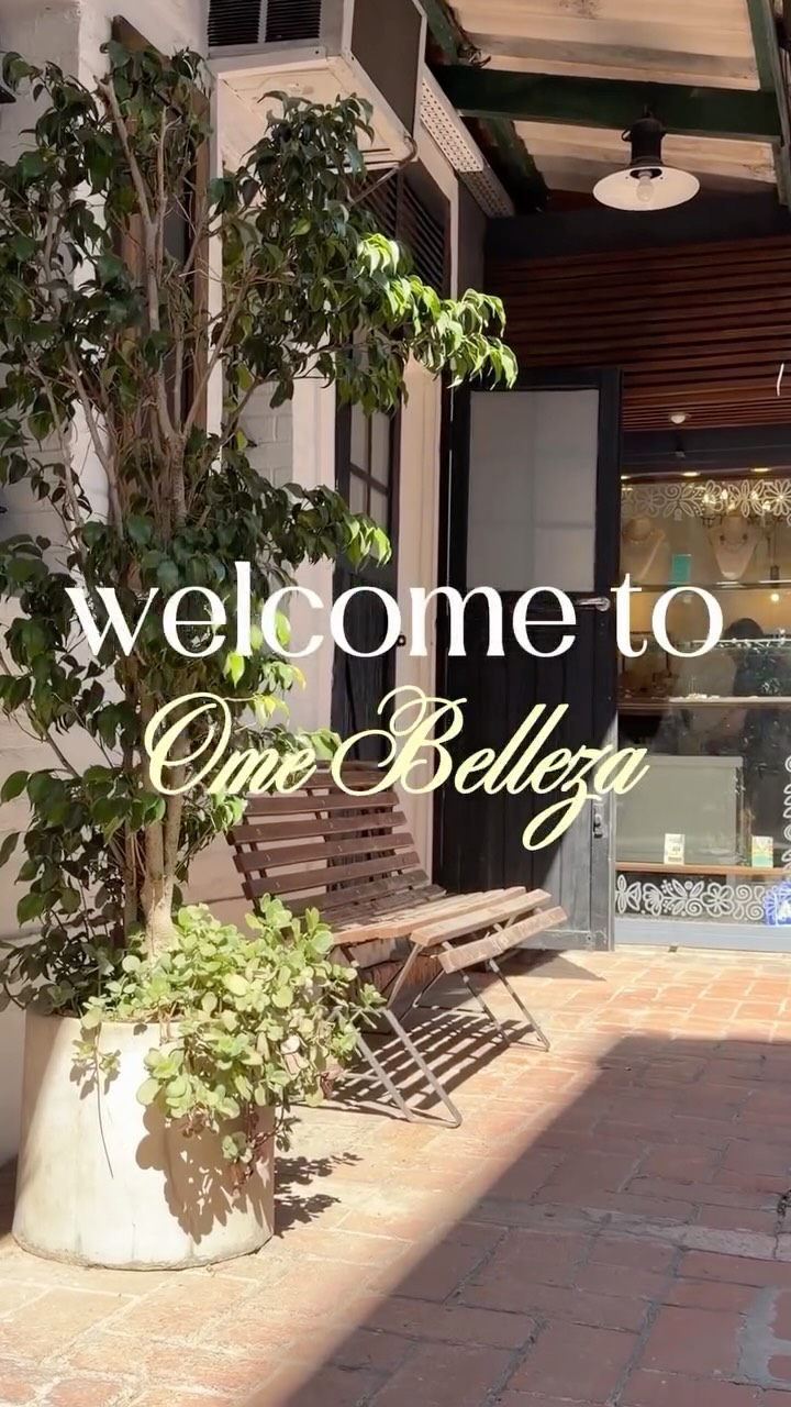 Entrada de Ome Belleza: patio de ladrillo, banco de madera y plantas, con el texto «welcome to Ome Belleza»
